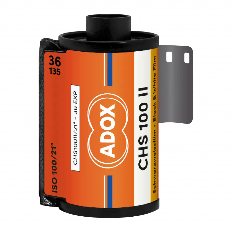A 35 mm cassette of ADOX CHS 100 II, leader out, orange label with the ADOX double-circle mark, marked ISO 100/21°, 36 exposures, Schwarzweissfilm