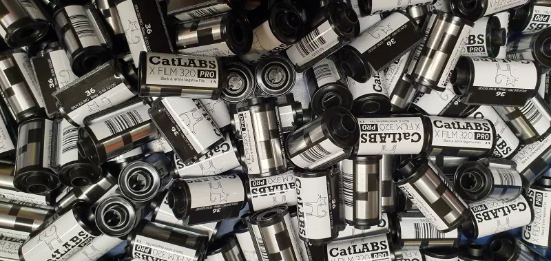 A heap of 35 mm cassettes of CatLABS X Film 320 Pro, black and white labels