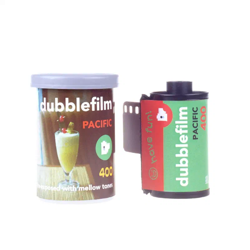A dubblefilm Pacific 400 canister and 35 mm cassette on white, the canister showing a cocktail glass on a table