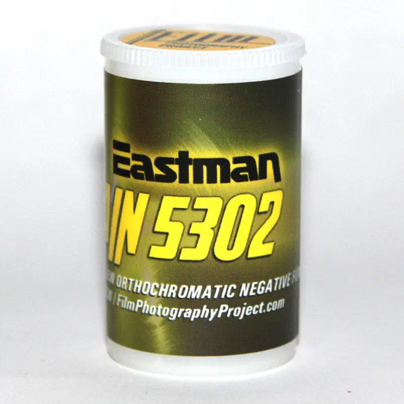 A 35 mm canister in olive and yellow lettered Eastman FINE GRAIN 5302, marked ORTHOCHROMATIC NEGATIVE FILM and FilmPhotographyProject.com
