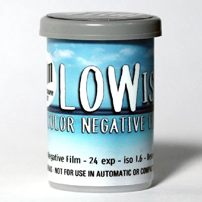 A 35 mm canister lettered LOW ISO in white over a blue sky, marked COLOR NEGATIVE FILM, 24 exp, iso 1.6