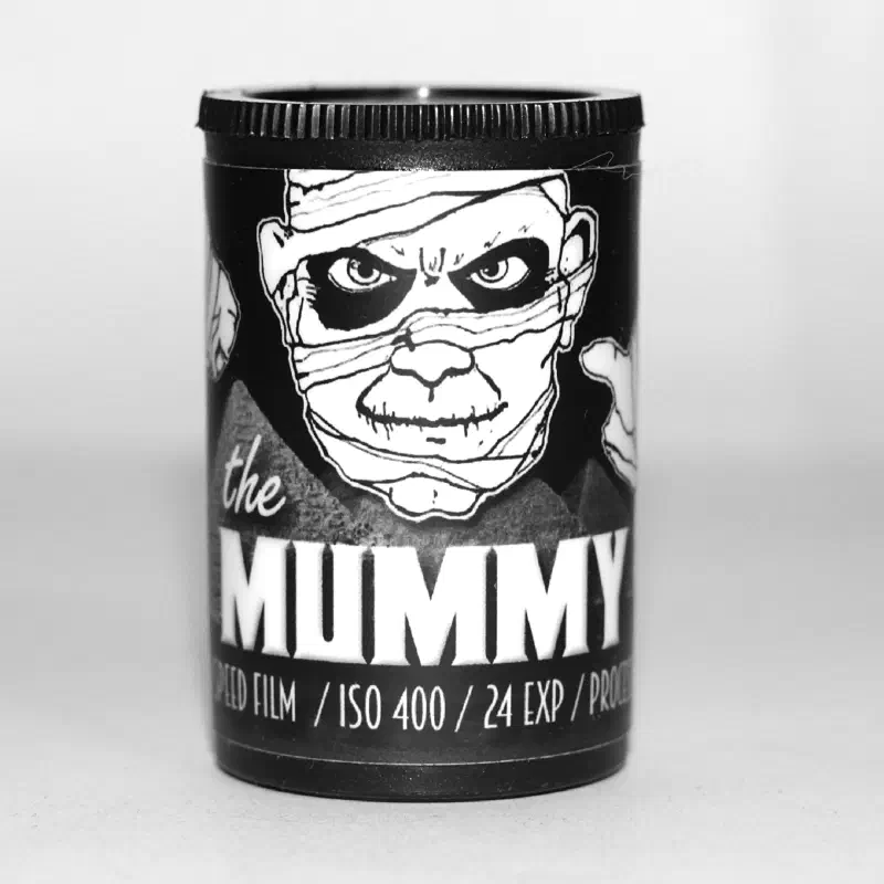 A black 35 mm canister lettered the MUMMY in white under a drawing of a bandaged face, marked ISO 400 / 24 EXP