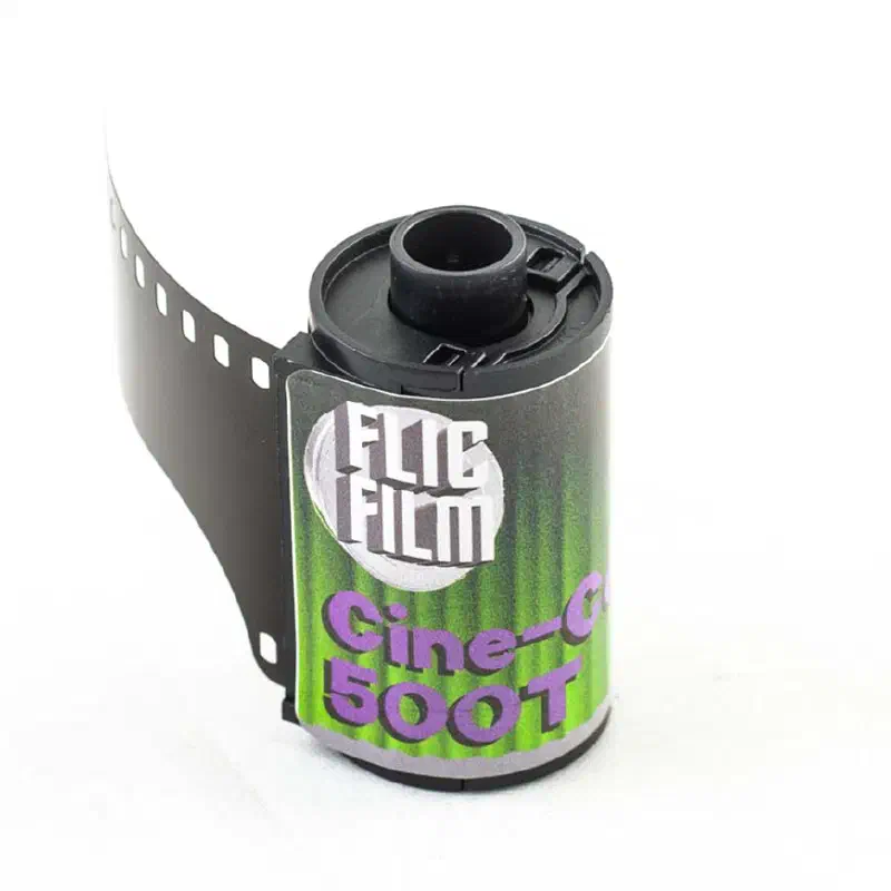 A 35 mm cassette of FLIC FILM Cine-Color 500T with its leader out, green label lettered in violet