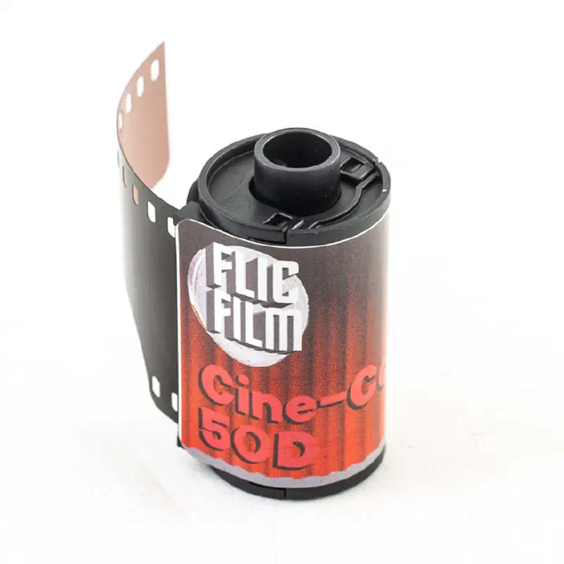 A 35 mm cassette of FLIC FILM Cine-Color 50D with its leader out, red ribbed label