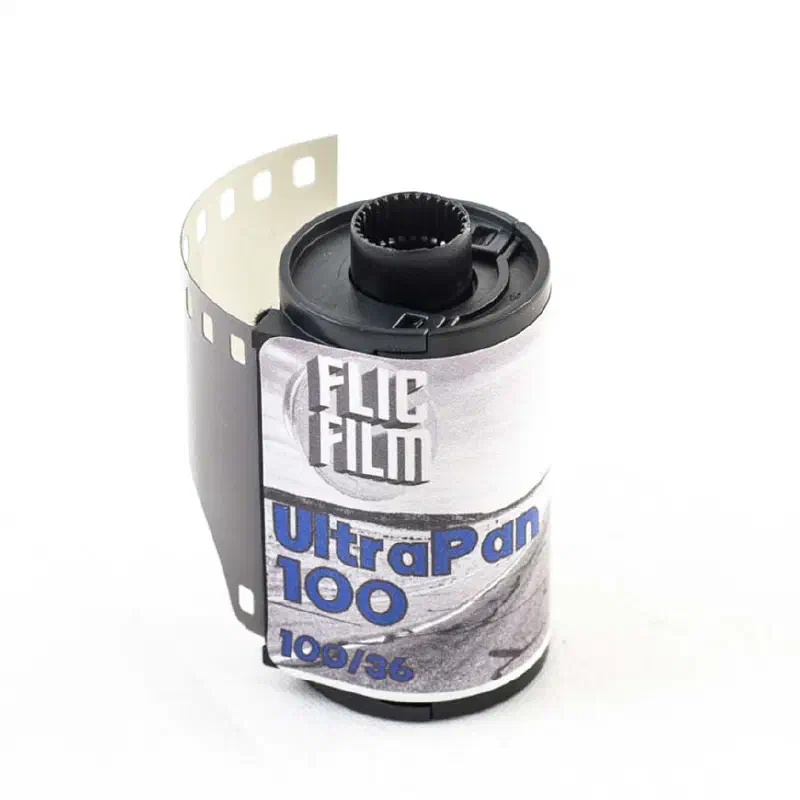 A 35 mm cassette of FLIC FILM UltraPan 100 with its leader out, a black-and-white photograph printed on the label, marked 100/36