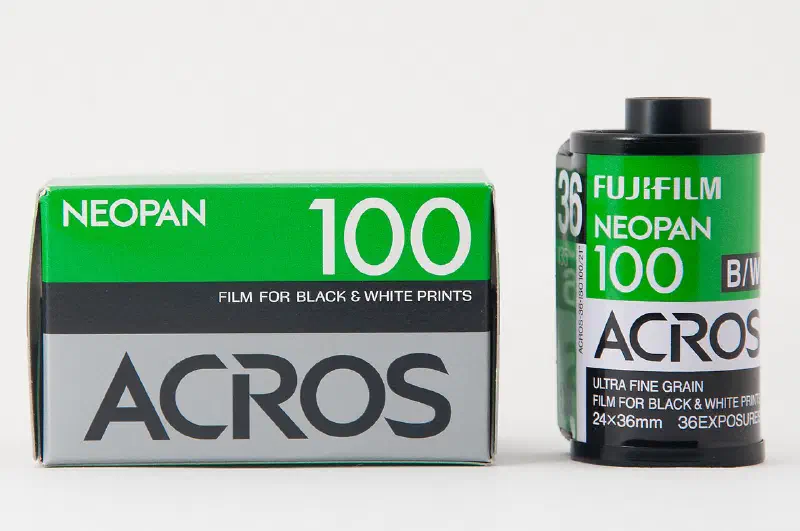 A green and white FUJIFILM NEOPAN 100 ACROS carton standing beside its 35 mm cassette, marked FILM FOR BLACK & WHITE PRINTS and ULTRA FINE GRAIN