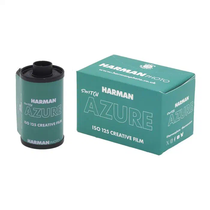 A 35 mm cassette of HARMAN SWITCH AZURE beside its dark teal carton, marked ISO 125 CREATIVE FILM