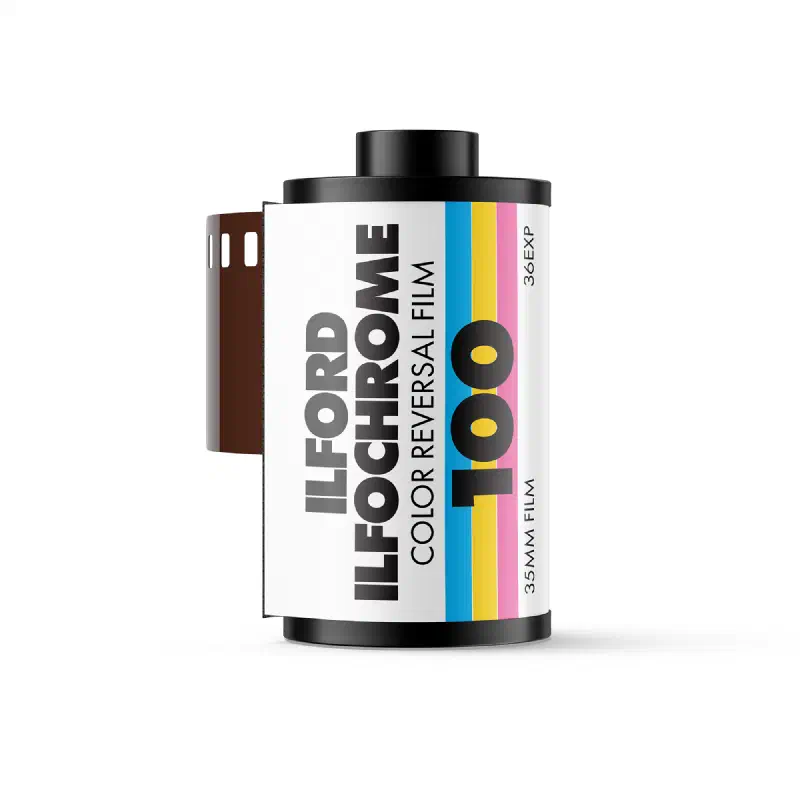 A 35 mm cassette of ILFORD ILFOCHROME 100 colour reversal film, leader out, white label banded in cyan, yellow and pink, marked 36EXP