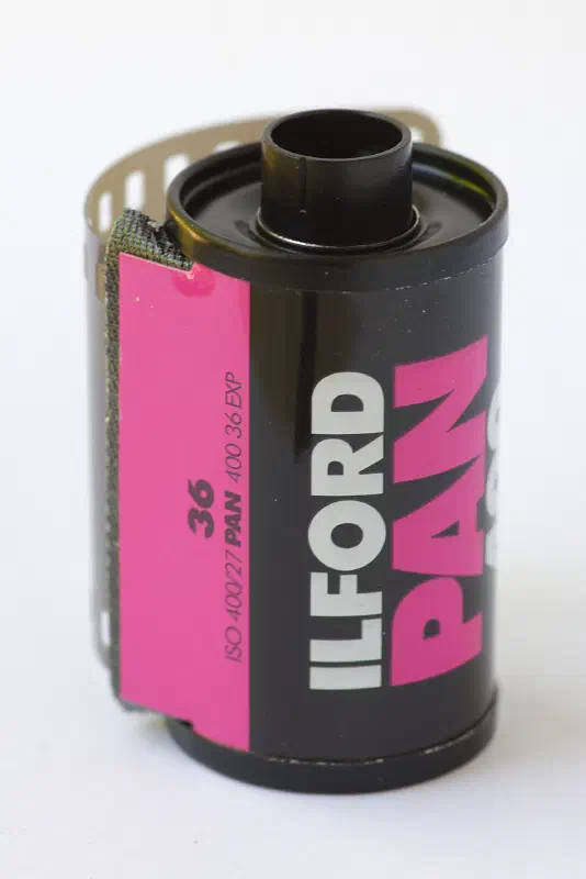 A 35 mm cassette of ILFORD PAN 400, black with a magenta panel lettered in white, marked 36 EXP