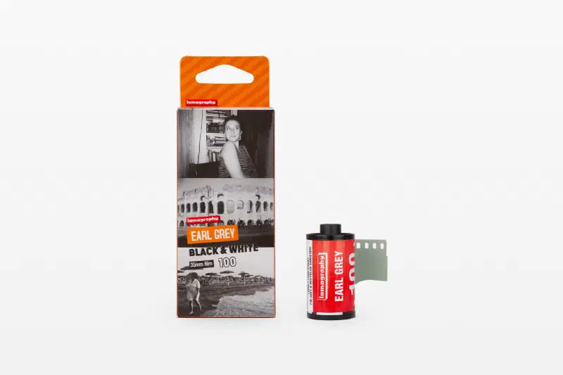 An Earl Grey Black & White carton printed with sample frames, beside a red 35 mm cassette and leader, marked 35mm film 100