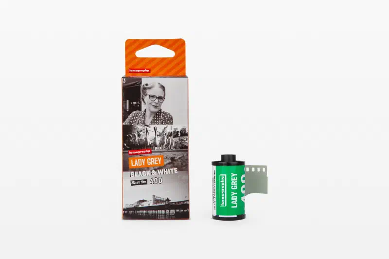 A Lady Grey Black & White carton printed with sample frames, beside a green 35 mm cassette and leader, marked 35mm film 400