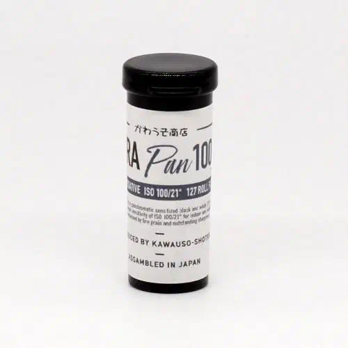 A 127 roll of Rera Pan 100S standing upright, its black-and-white label facing the camera