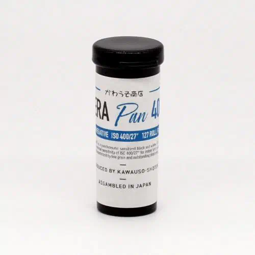 A 127 roll of Rera Pan 400 standing upright, its blue-and-white label facing the camera