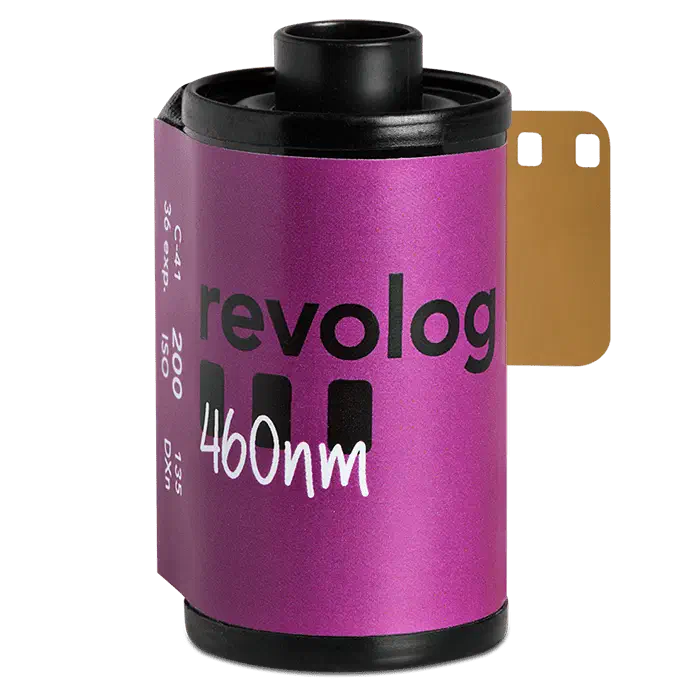 A 35 mm cassette of revolog 460nm on a green ground, its label a magenta-to-purple gradient lettered in white, leader out