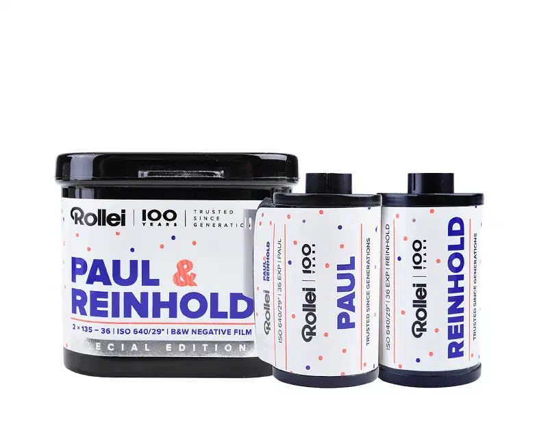 A white Rollei tin lettered PAUL & REINHOLD in blue and red and marked 2 × 135 - 36 | ISO 640/29° | B&W NEGATIVE FILM, standing behind the two 35 mm cassettes it holds, one labelled PAUL and one REINHOLD